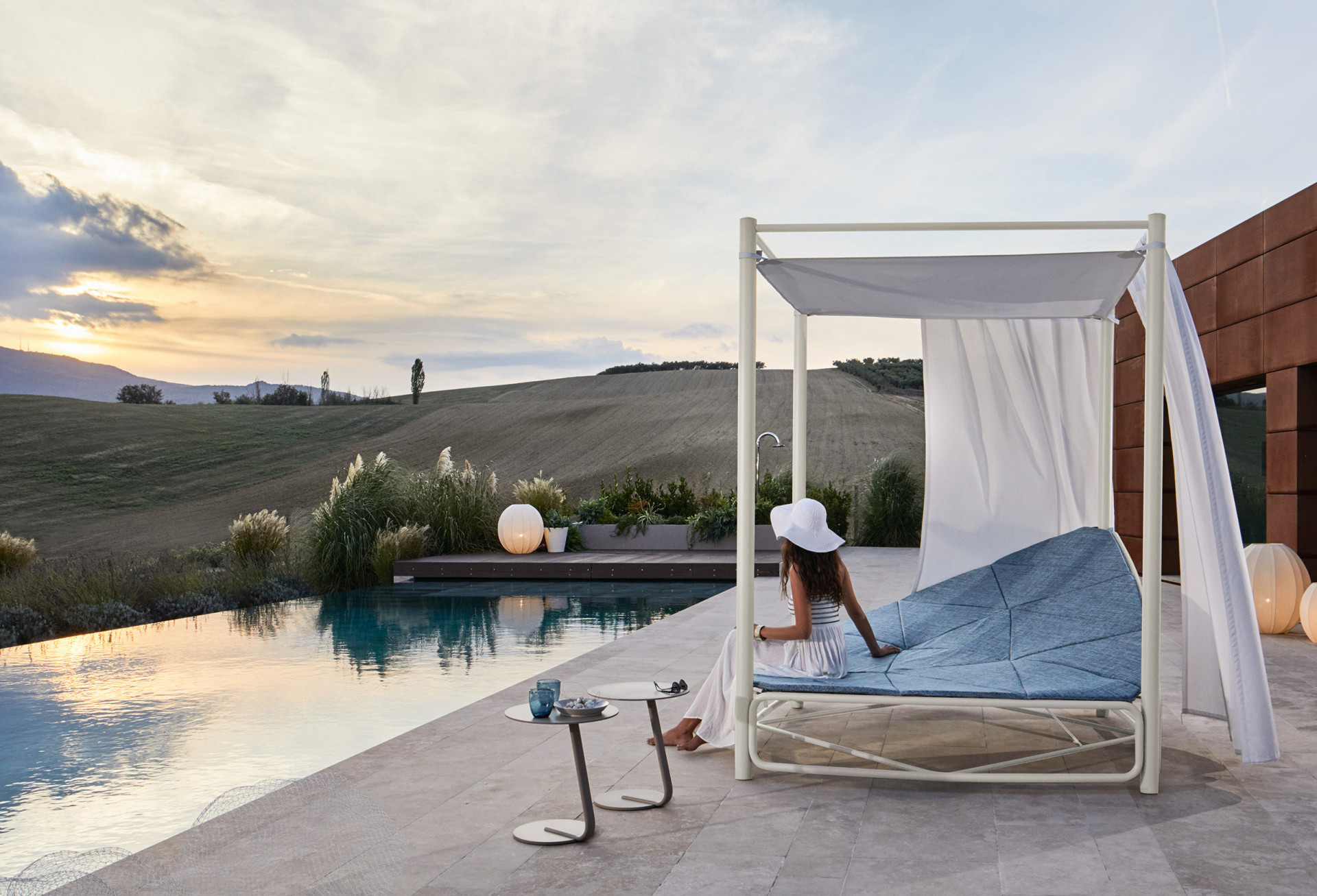 A luxurious outdoor swimming pool daybed placed adjacent to a lush green field, offering a serene and elegant setting for relaxation and enjoyment.